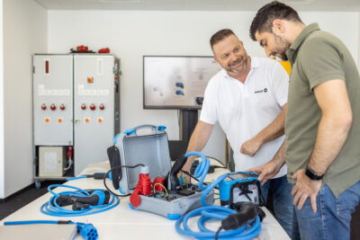 Seminarleiter zeigt Seminarteilnehmer Gerätschaften rund um Elektromobilität.